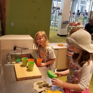 Kids engaged in a fun kitchen activity, exploring their creativity with colorful cups and pretend food.