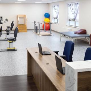 A spacious rehabilitation center with exercise equipment and a workstation.