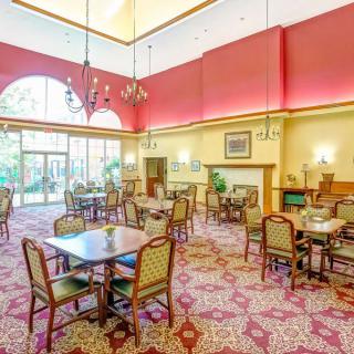 A spacious dining area with elegant tables and chairs, featuring a high ceiling and decorative lighting.