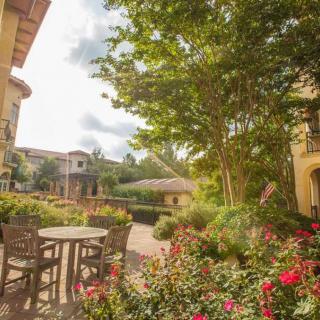 A serene garden patio surrounded by lush greenery and vibrant flowers.