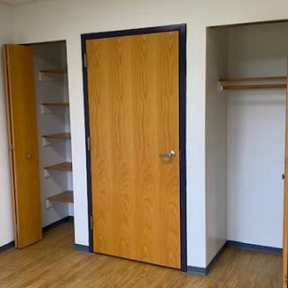 An empty room with open closets and wooden doors.