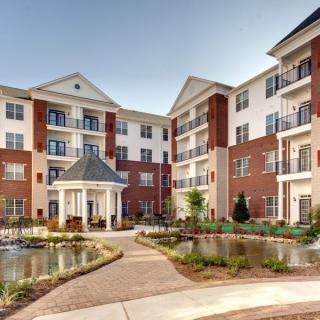 A modern residential apartment building with landscaped gardens and a small pond.