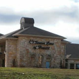 A stone-faced building with a prominent sign, set against a cloudy sky.