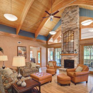 A cozy living room with a wooden ceiling, stone fireplace, and comfortable seating.