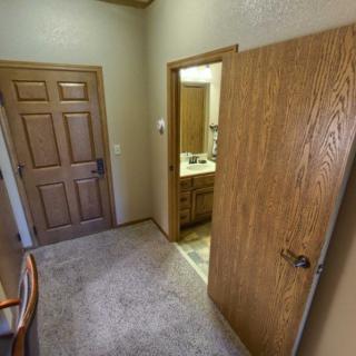 View of a bedroom leading to a bathroom with wooden doors.