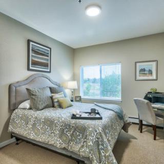 A cozy and well-decorated bedroom featuring a neatly made bed, a desk with a chair, and soft lighting.