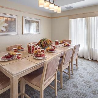 A well-decorated dining room with a table set for a meal, featuring elegant decor and ample natural light.