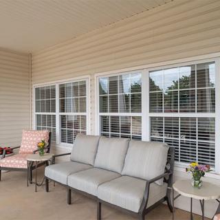 A cozy patio area with cushioned seating and side tables in front of large windows.