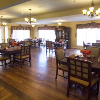 A spacious dining area with wooden flooring and elegant chandeliers.