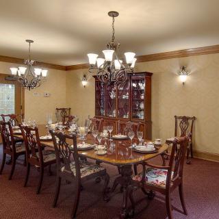 An elegantly set dining room with a long table and chandeliers.
