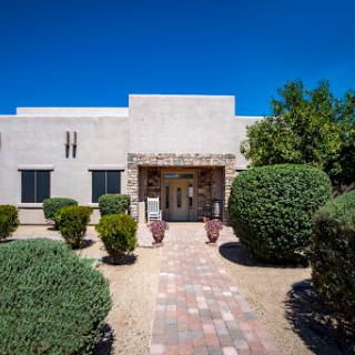 A serene view of a modern building surrounded by neatly trimmed hedges and a clear blue sky.