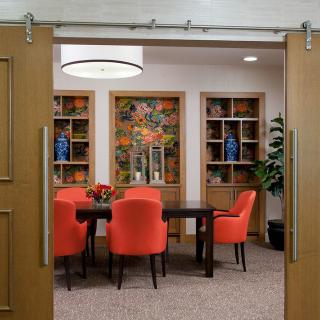 A modern dining room with vibrant red chairs and decorative bookshelves.