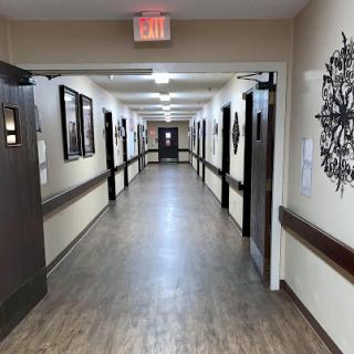 A view of a well-lit hallway adorned with artwork, featuring multiple doors along the sides.