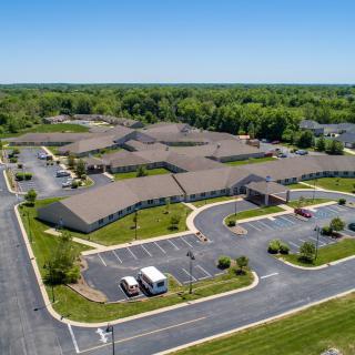 Aerial view of a large building complex surrounded by greenery and parking lots.