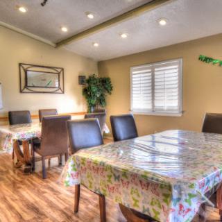 A cozy and well-lit dining room featuring tables with colorful tablecloths and comfortable chairs.