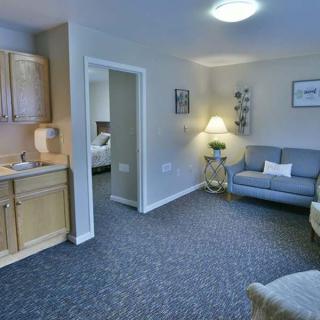 A cozy living room with a sofa, lamp, and kitchenette in view.