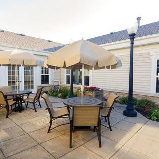 A cozy outdoor patio area with tables, chairs, and umbrellas adjacent to a building.