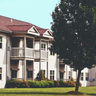 A view of a residential apartment complex with balconies and a tree in the foreground.