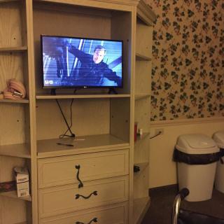 A TV on a shelf in a room with floral wallpaper.