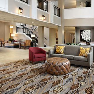 A modern hotel lobby featuring stylish furniture and a patterned carpet.