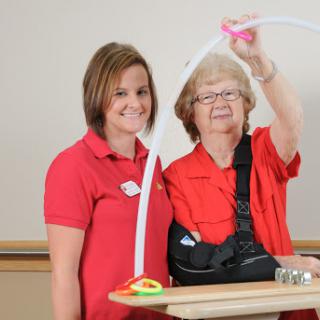 A caregiver and an elderly woman engage in a therapeutic activity, showcasing the importance of rehabilitation in healthcare.
