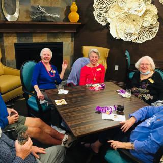 A group of elderly people enjoying a social gathering around a table indoors.