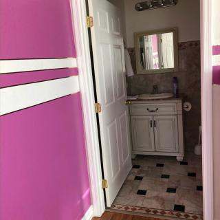 A small bathroom with pink walls, a white vanity, and a tiled floor.