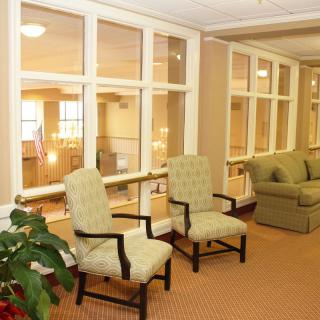 A cozy waiting area with chairs and a sofa, bordered by large windows.