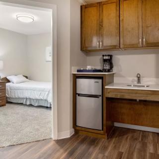 A modern apartment with a kitchenette and an adjoining bedroom.