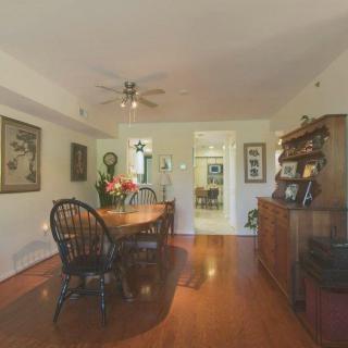 A cozy dining room with wooden flooring, a large table surrounded by chairs, and decorated with artwork on the walls.