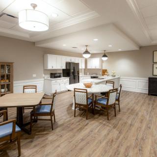 A modern kitchen and dining area featuring wood flooring, stylish lighting, and elegant furniture.