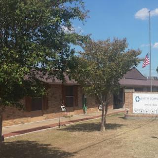 A brick building featuring a flag and trees, accompanied by signage in front.