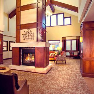 A modern and cozy living room featuring a central fireplace, elegant furniture, and large windows.
