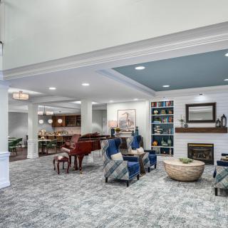 A spacious living room featuring a grand piano, comfortable seating area, and a cozy fireplace.