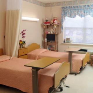 A shared hospital room with two beds and medical equipment.