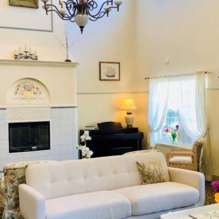 A cozy living room featuring a white sofa, elegant chandelier, and a classical fireplace.