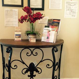 A decorative table with flowers and brochures against a wall adorned with framed certificates.