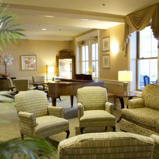 A cozy sitting area with chairs, a sofa, and a table in a warmly lit room.