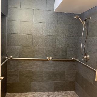 Accessible shower with grab bars and a handheld showerhead.