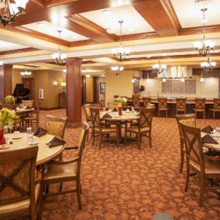 A spacious and warmly lit restaurant dining area with neatly arranged tables and chairs.