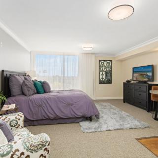 A modern and cozy bedroom with a neatly made bed, stylish furniture, and a soft carpet.
