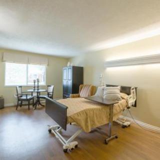 A well-lit hospital patient room featuring a bed, seating area, and window.