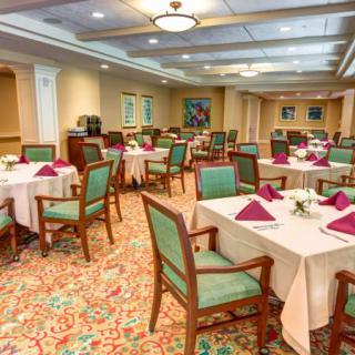 An elegantly arranged dining room with neatly set tables and chairs, featuring floral decorations and colorful napkins.