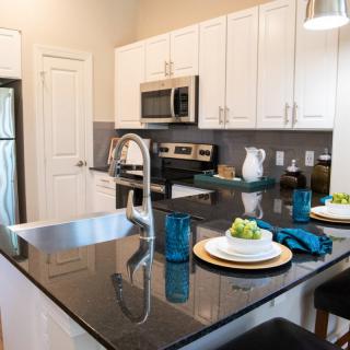 A modern kitchen with granite countertops and stainless steel appliances, featuring a cozy dining area with bar stools.