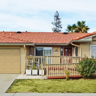 A charming single-story suburban house with a front porch and well-maintained yard.