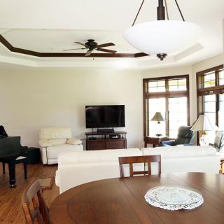 A spacious living room featuring comfortable seating, a piano, and a large television.
