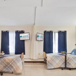 A cozy bedroom with two neatly arranged beds and blue curtains.