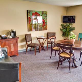 A cozy interior space featuring a seating area with a table, chairs, a wall-mounted television, and decorative artwork.