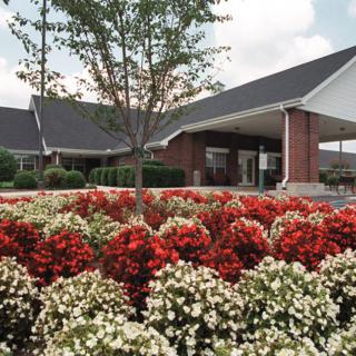 A brick building surrounded by vibrant red and white flowers in a well-maintained garden.