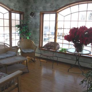A sunlit room with large windows, wicker furniture, and a vibrant flower arrangement.
